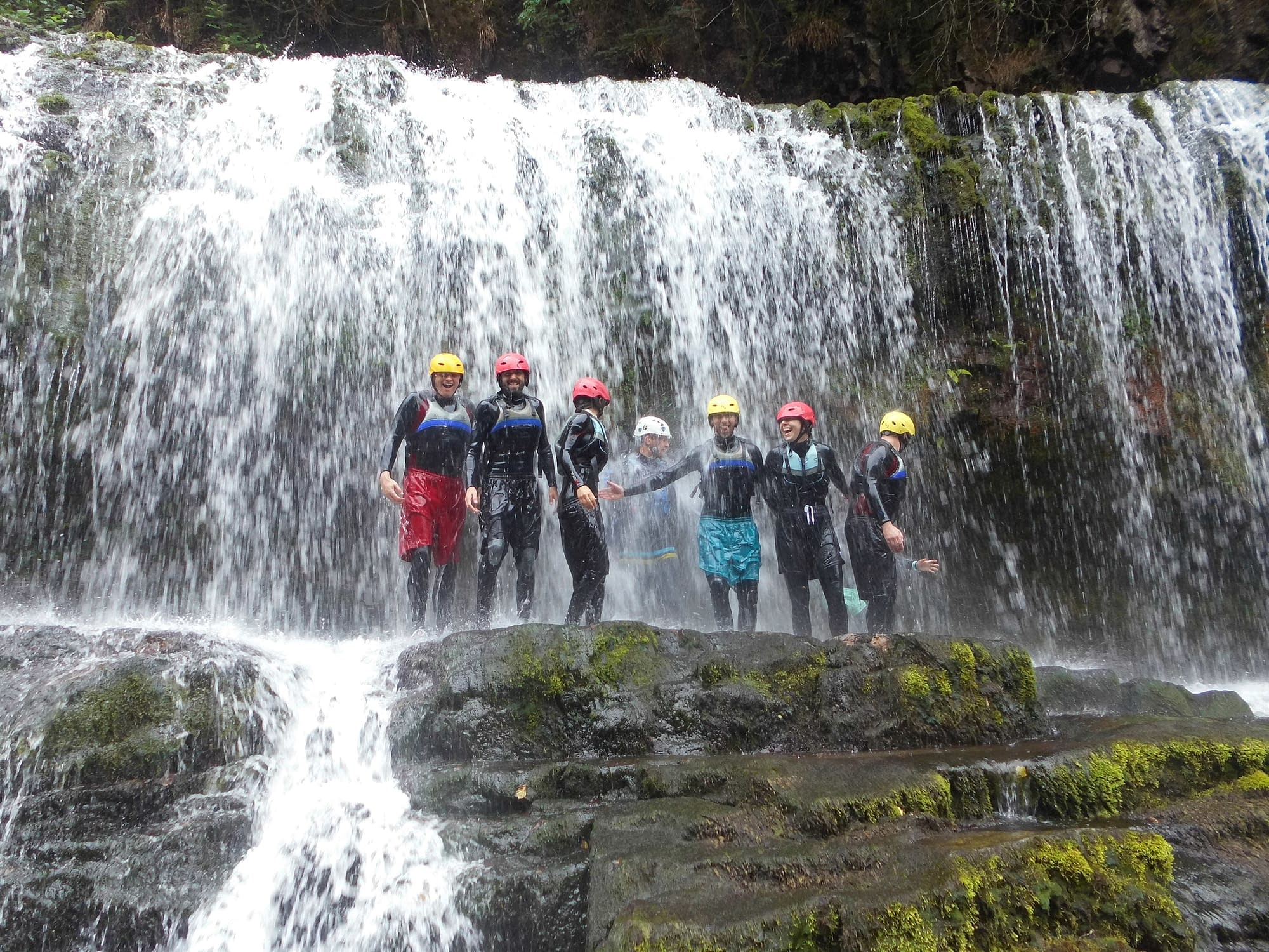 Group standing on a cliff under a waterfall whilst gorge scrambling