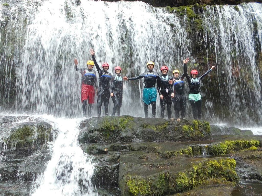 Group of guys in front of a waterfall whilst gorge scrambling near Cardiff, South Wales