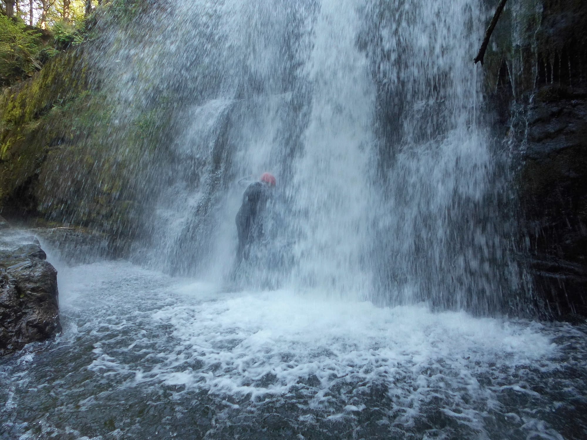 Walking through a waterfall on a canyoning activity near Cardiff